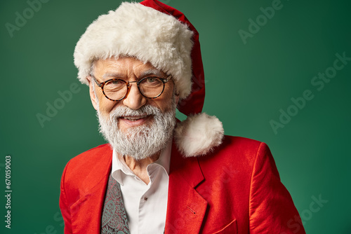 elegant bearded Santa with red hat and glasses smiling cheerfully at camera, Christmas concept