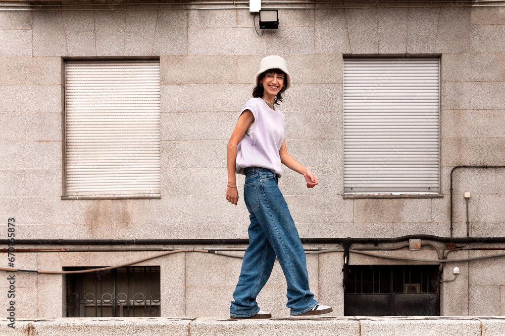 Young woman walking on stone border in street Young woman walking on stone border in street