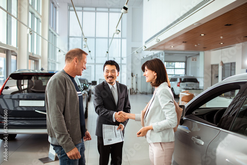Couple finalizing a car purchase with a dealership representative photo