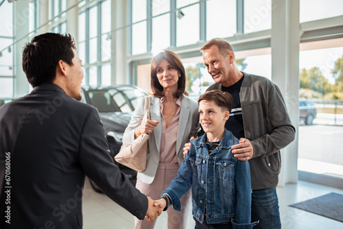 Family shaking hands with a salesperson after purchasing a car