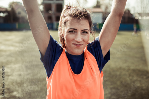 Determined female football player raises her arm in confidence on the field photo