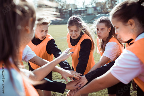Young female football players unite with hands together on the field photo