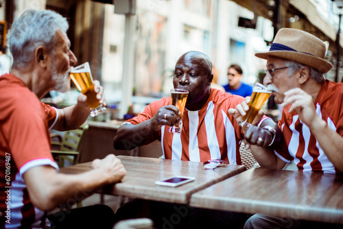 Senior sports fans sharing a laugh over beers at a street cafe photo