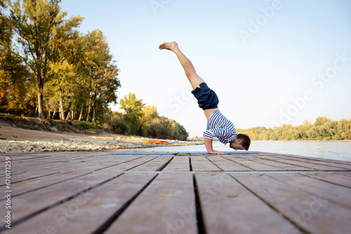 Active man practicing young on the pier by the river