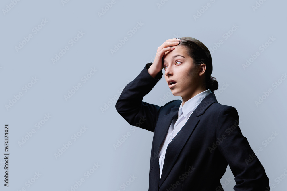 Surprised teenage female looking in profile at copy space, grey background Surprised teenage female looking in profile at copy space, grey background