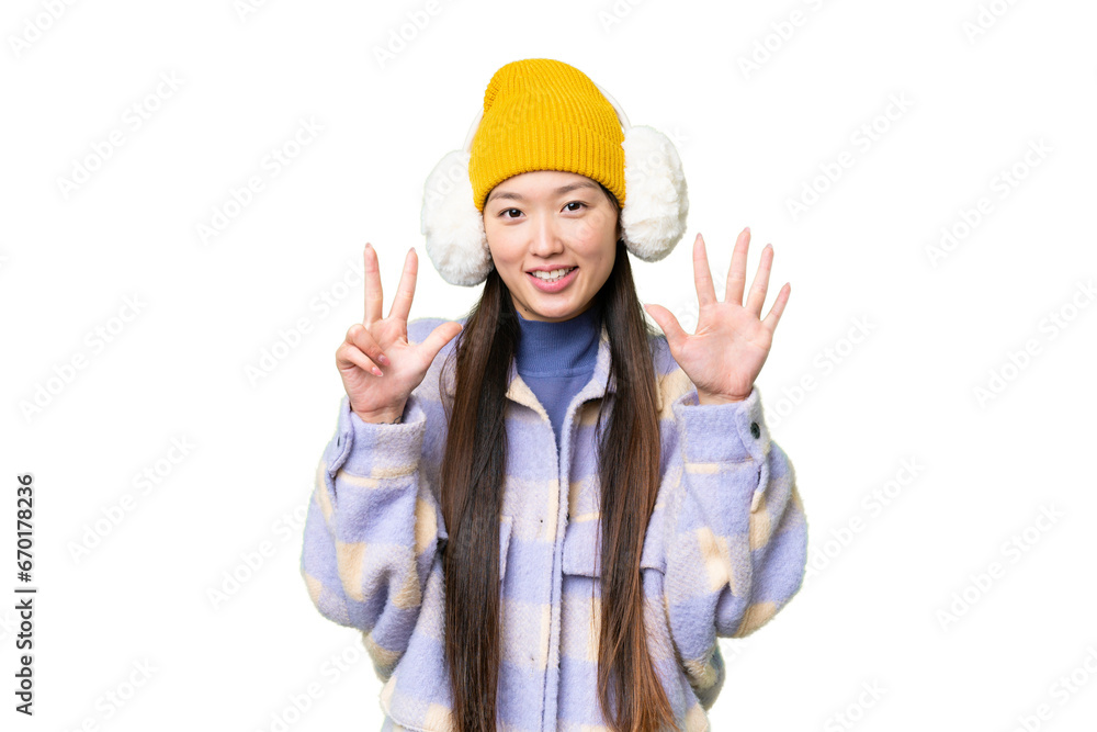 Young Asian woman wearing winter muffs over isolated chroma key background counting eight with fingers Young Asian woman wearing winter muffs over isolated chroma key background counting eight with fingers