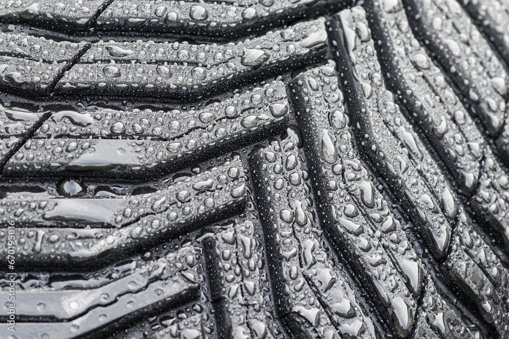 Closeup of the tire tread pattern. Car tyre tracks with waterdrops