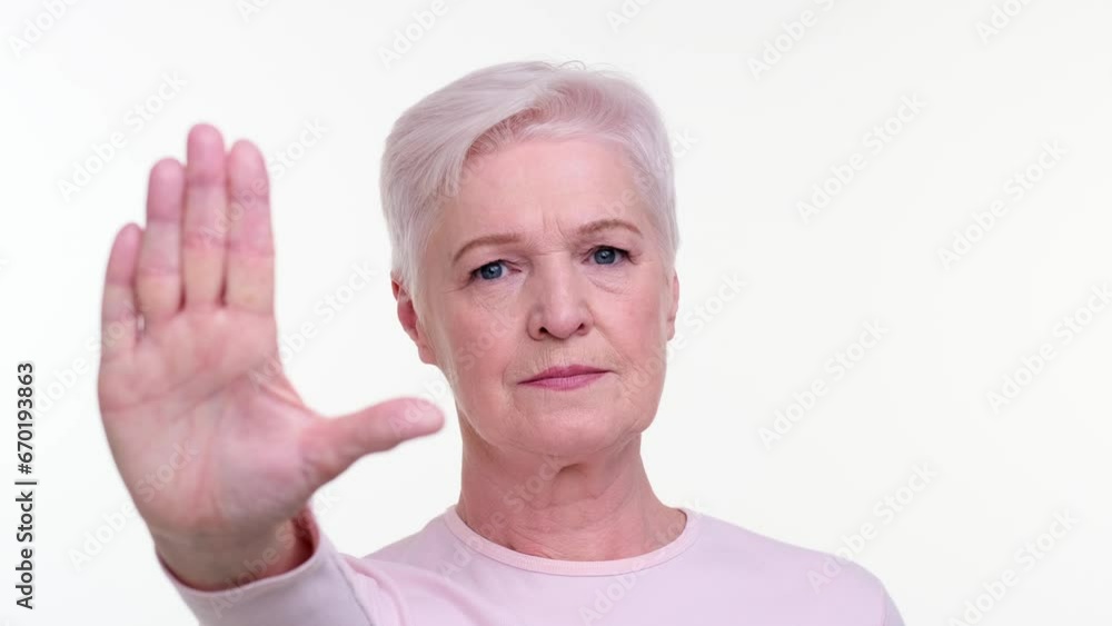 Woman confidently displays the universal stop gesture with hand, palm facing outward. Her firm expression conveys authority and assertiveness, capturing a moment of clear boundary setting. Woman confidently displays the universal stop gesture with hand, palm facing outward. Her firm expression conveys authority and assertiveness, capturing a moment of clear boundary setting.
