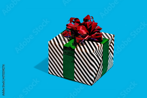 Striped gift box with red bow on blue surface photo