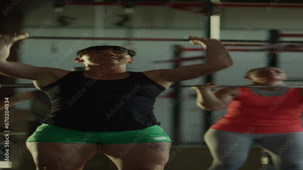 Panning rack focus shot from man to woman lifting barbells in gymnasium - vertical video / Lehi, Utah, United States Panning rack focus shot from man to woman lifting barbells in gymnasium - vertical video / Lehi, Utah, United States