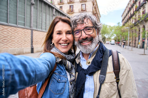 Фотография Selfie portrait smiling mature Caucasian tourist couple posing outdoors