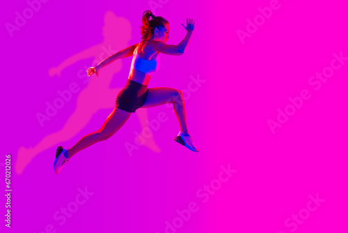 Fototapeta Naklejka Na Ścianę i Meble -  Sportive beautiful woman training with athletic body and sportswear doing workout, colorful lighting and background