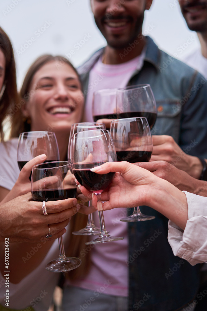 Vertical photo focus on red wine glasses. Friends toasting, celebrating together. People having fun outdoors. Copy space. Vertical photo focus on red wine glasses. Friends toasting, celebrating together. People having fun outdoors. Copy space.