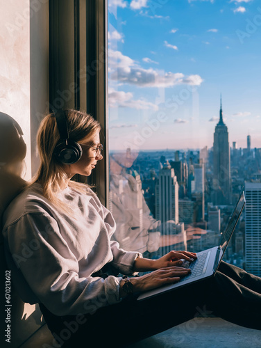Canvas Print Caucasian female listening to music in headphones while working on laptop comput