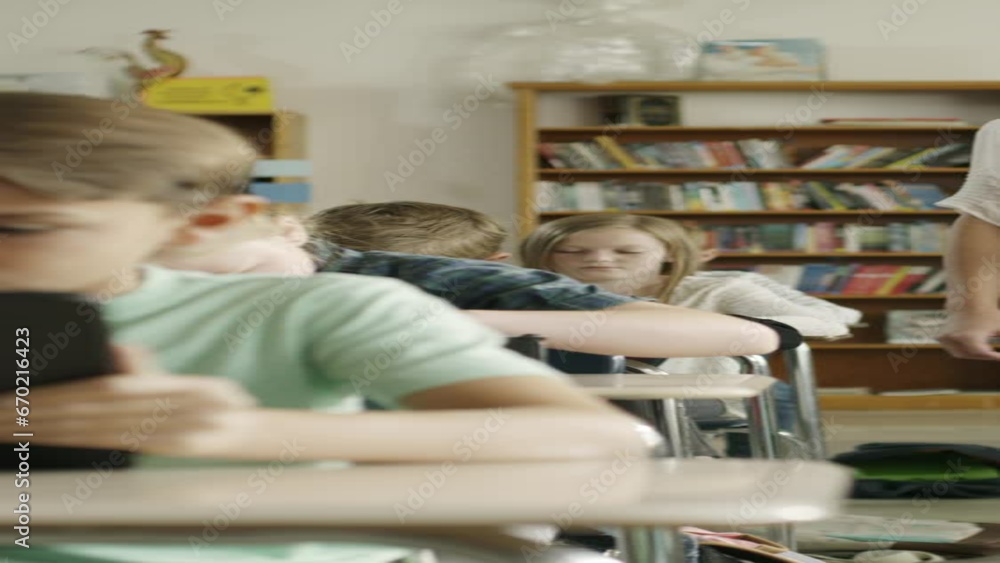Panning shot of teacher assisting children in classroom reading digital tablets - vertical video / Provo, Utah, United States Panning shot of teacher assisting children in classroom reading digital tablets - vertical video / Provo, Utah, United States