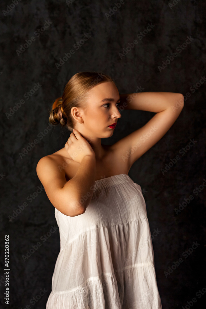 Portrait of pretty teen girl in doll image posing gesturing hands at black background, thoughtful looking away. Lovely teenager lady in white, studio shot. Beauty body care concept. Copy ad text space