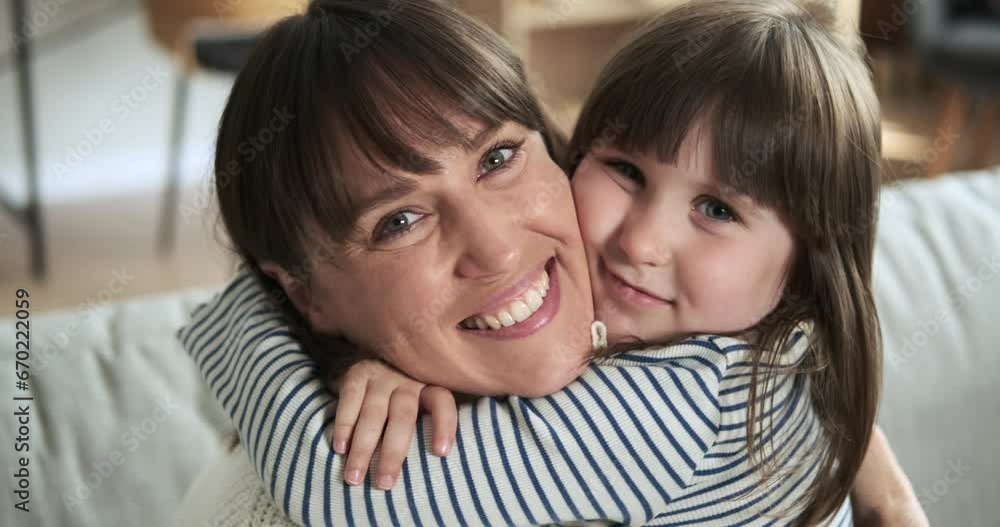 Heartwarming portrait captures a moment of joy as a smiling mother and daughter gaze into the camera while sitting of sofa, radiating happiness and love. Heartwarming portrait captures a moment of joy as a smiling mother and daughter gaze into the camera while sitting of sofa, radiating happiness and love.