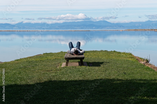 A person lies with their hands clasped behind their head, admiring the view out over the inlet at the old wharf in Motueka photo
