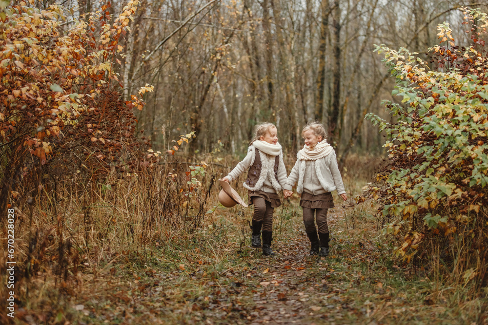 Twin girls play in the autumn park.