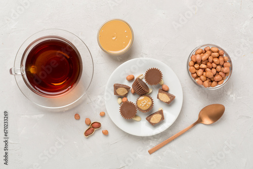 Delicious peanut butter cups with tea on concrete background, top view