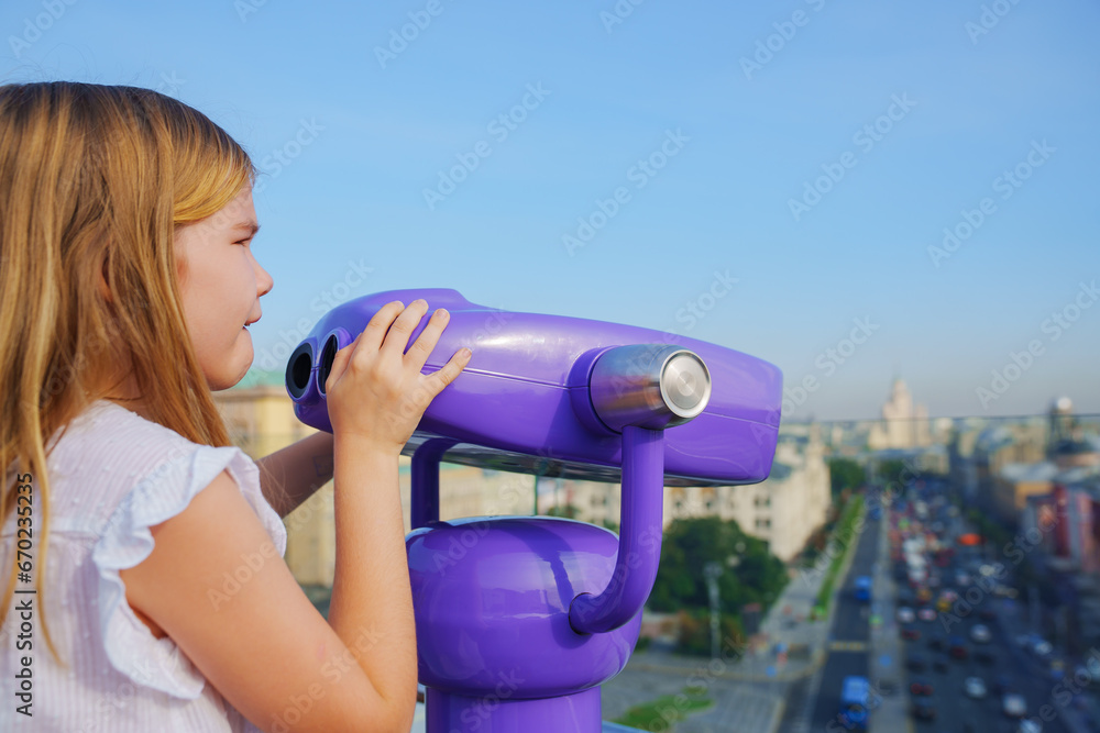 a teenage girl looks into the Binoscope from the observation deck at a height. 
