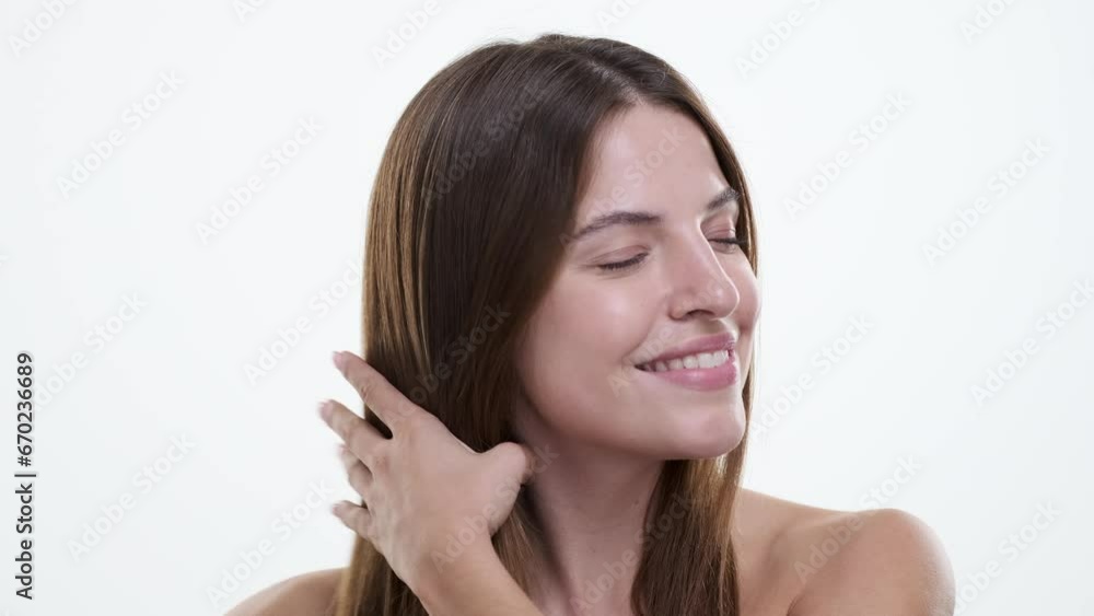 Woman attentively cares for hair, gently gliding a comb through locks with a focused expression against a pristine white backdrop. Her graceful movements reflect a sense of self-love and care. Woman attentively cares for hair, gently gliding a comb through locks with a focused expression against a pristine white backdrop. Her graceful movements reflect a sense of self-love and care.