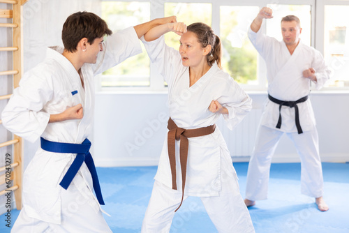Woman and man in kimono sparring together in gym during karate training