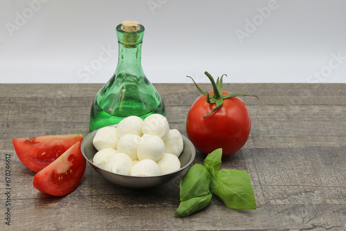 Bowl of Mozzarella, tomato, basil and olive oil in a bottle - ingredients for a healthy dish