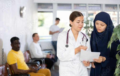 Nurse discusses documents with young Asian woman in a veil