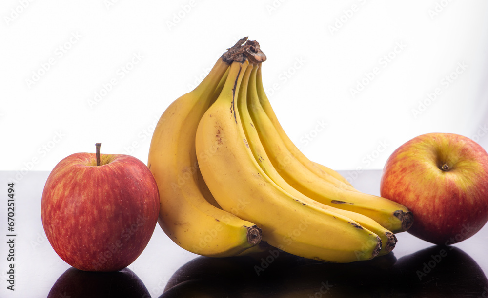 Bananas and apples, a beautiful composition with bananas and apples on a reflective surface with a light background, selective focus.