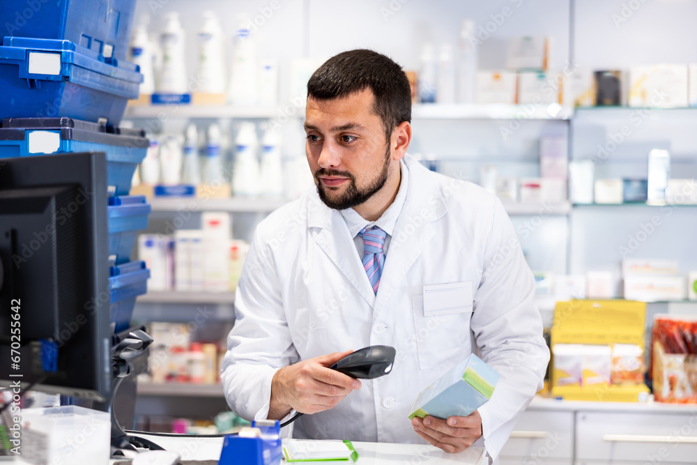 Male pharmacist scans the barcode of product at the checkout in a pharmacy