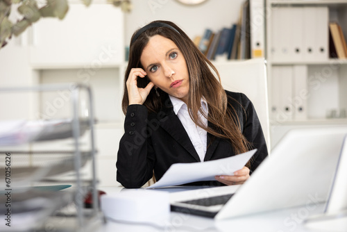 Portrait of female secretary in suit sitting at table in her workplace. © JackF