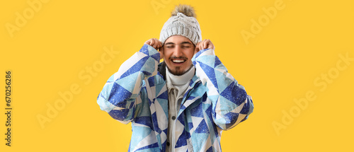 Stylish young man in winter clothes on yellow background photo