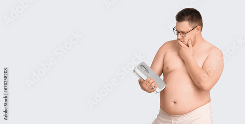 Overweight man holding scal...