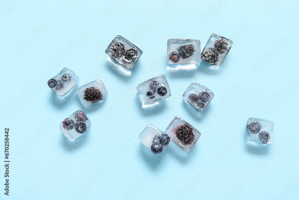 Frozen berries in ice cubes on blue background Frozen berries in ice cubes on blue background