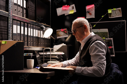 Elderly police officer analyzing confidential federal files, working at criminal investigations in arhive room. Senior private detective checking missing person case, looking at victim report