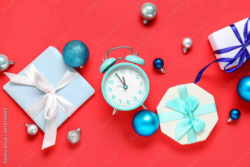 Composition with alarm clock, Christmas gifts and balls on red background Composition with alarm clock, Christmas gifts and balls on red background