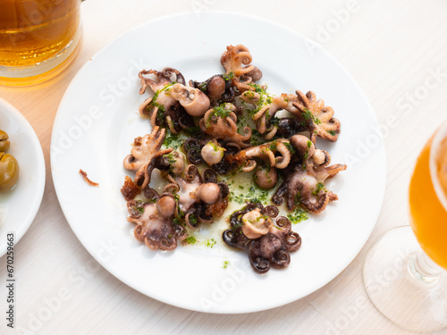 Fried octopus dish with herbs and sauce and beer