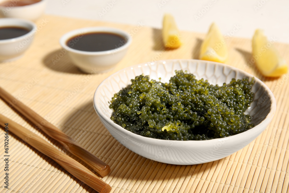 Bowl with healthy seaweed, soy sauce and lemon slices on bamboo mat, closeup Bowl with healthy seaweed, soy sauce and lemon slices on bamboo mat, closeup