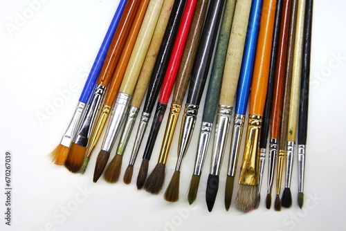 Many art brushes Lying on a white plane of different sizes and colors lie in a row sideways to each other. Different brushes for painting with oils, watercolors and gouache. beautiful background