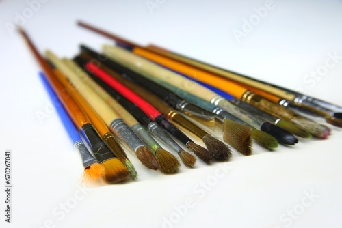 Many art brushes Lying on a white plane of different sizes and colors lie in a row sideways to each other. Different brushes for painting with oils, watercolors and gouache. beautiful background 