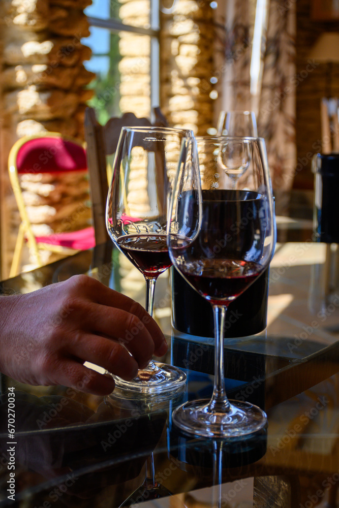 Tasting of red dry wine in Chateauneuf-du-Pape wine making village in France with green vineyards on large pebbles galets and sandstone clay soil
