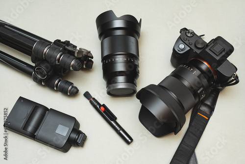 Modern photographic equipment, a mirrorless camera with a lens, an interchangeable lens, a flash, a tripod and a brush for cleaning lenses and other photographic equipment. photo