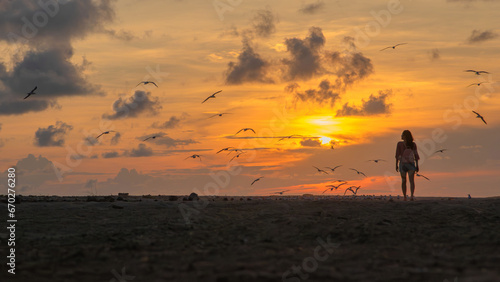 A woman looking at the sunset with birds flying in barra vieja Acapulco city Mexico