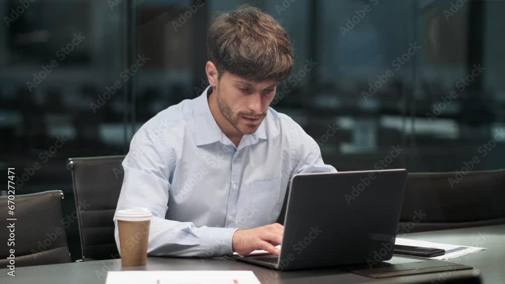In a bustling office environment, a diligent Caucasian employee is engrossed in work, meticulously managing tasks with a laptop and stacks of papers. His focused demeanor reflects dedication. In a bustling office environment, a diligent Caucasian employee is engrossed in work, meticulously managing tasks with a laptop and stacks of papers. His focused demeanor reflects dedication.