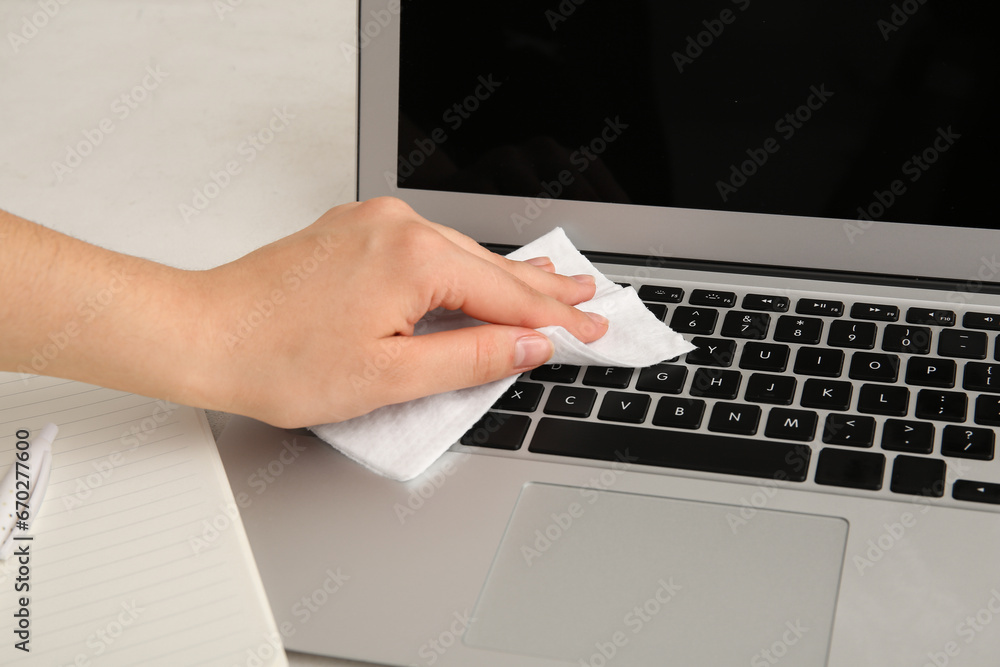 Young woman cleaning laptop on white table Young woman cleaning laptop on white table