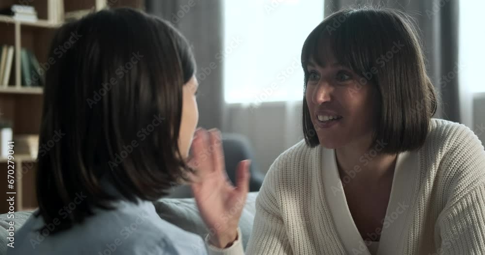 Surprised mother engages son with an intriguing story while they sit on the couch. Her captivating narrative create an enchanting scene of familial storytelling.