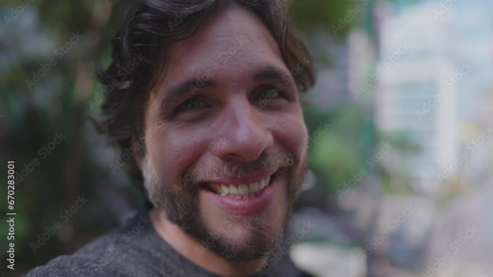 One happy handsome man smiling at camera standing outside at park One happy handsome man smiling at camera standing outside at park