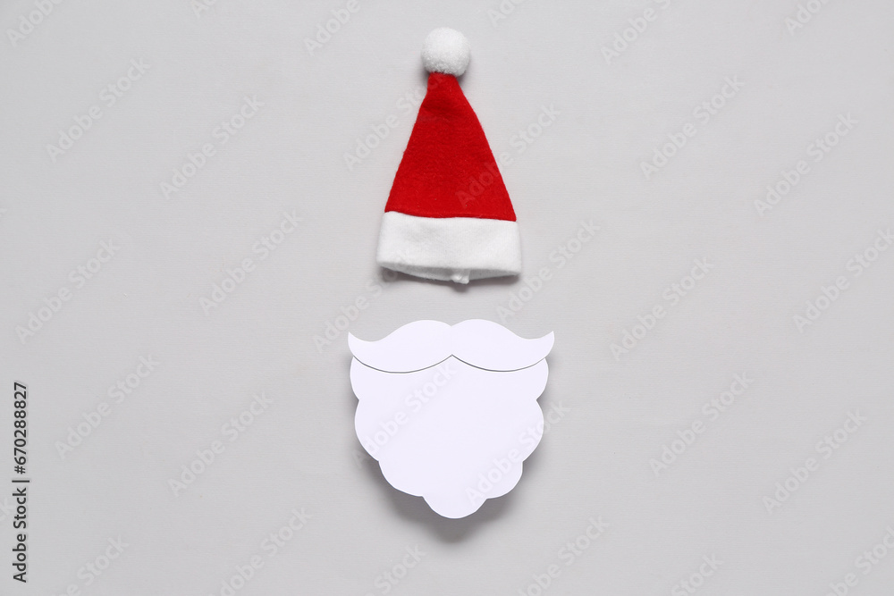 Santa hat with paper beard on grey background Santa hat with paper beard on grey background