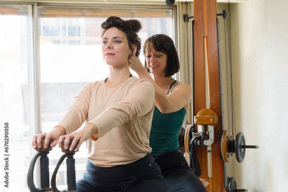 female exercise instructor correcting spine posture to her female student female exercise instructor correcting spine posture to her female student
